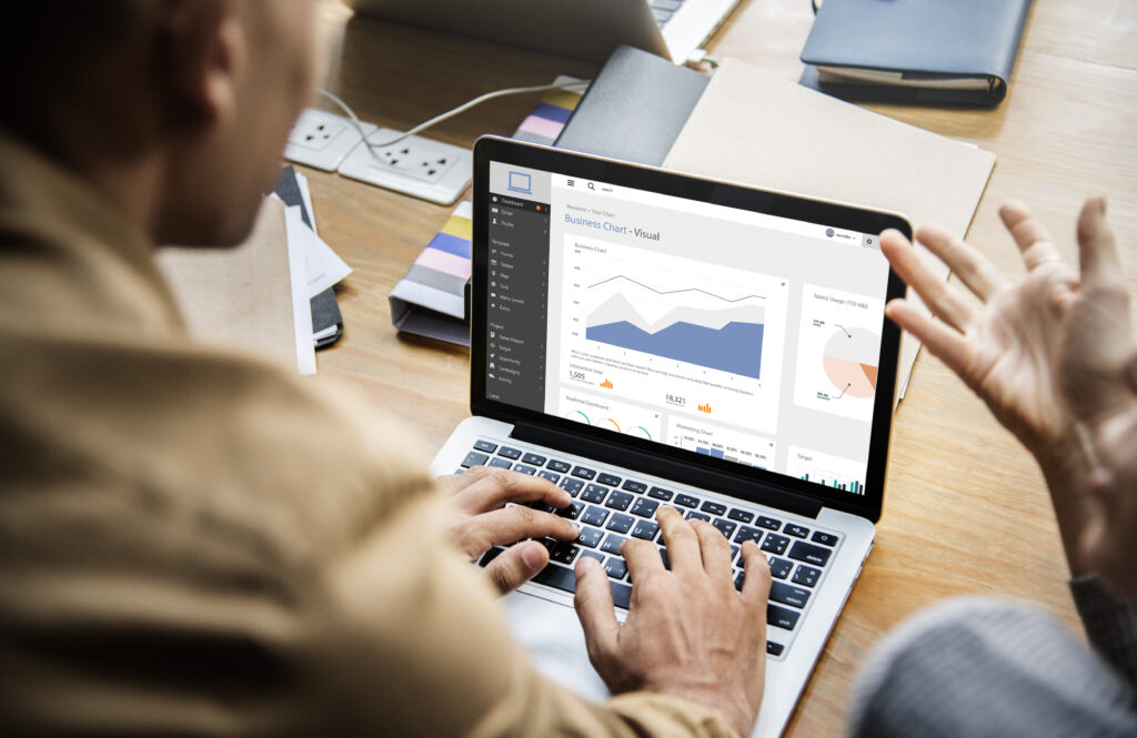Homem utilizando notebook para analisar dashboard de comunicação com gráficos e métricas em tela, acompanhando desempenho de campanhas e indicadores.