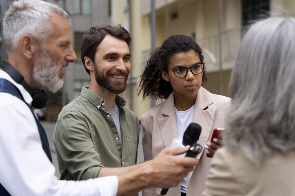 Executivo sendo entrevistado em frente às câmeras, com postura ereta e gestos controlados, representando boas práticas ao preparar clientes para entrevistas e reforçar a mensagem com linguagem corporal adequada.